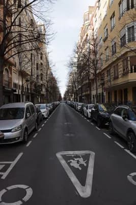 A street scene with parked cars and a pedestrian crossing sign.