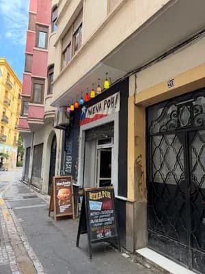 A street view of a restaurant with colorful hanging lights and a chalkboard menu outside.